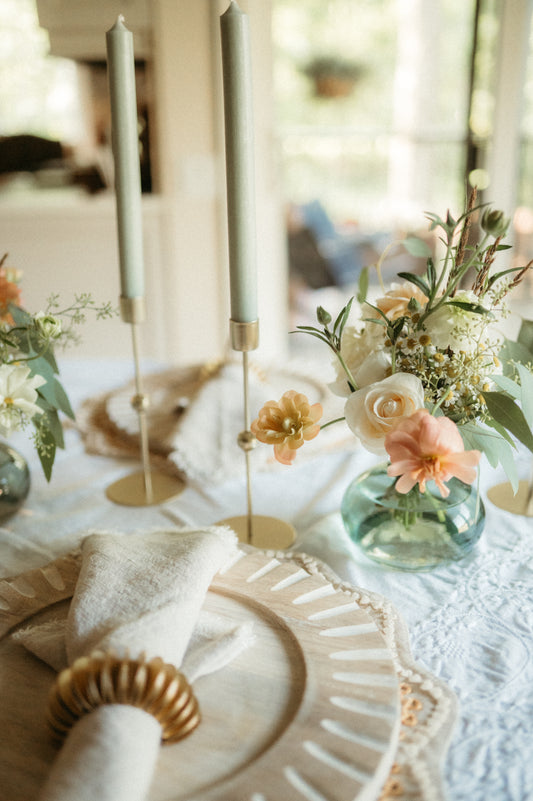 Table setting with floral arrangements, candles, and decorative plates.