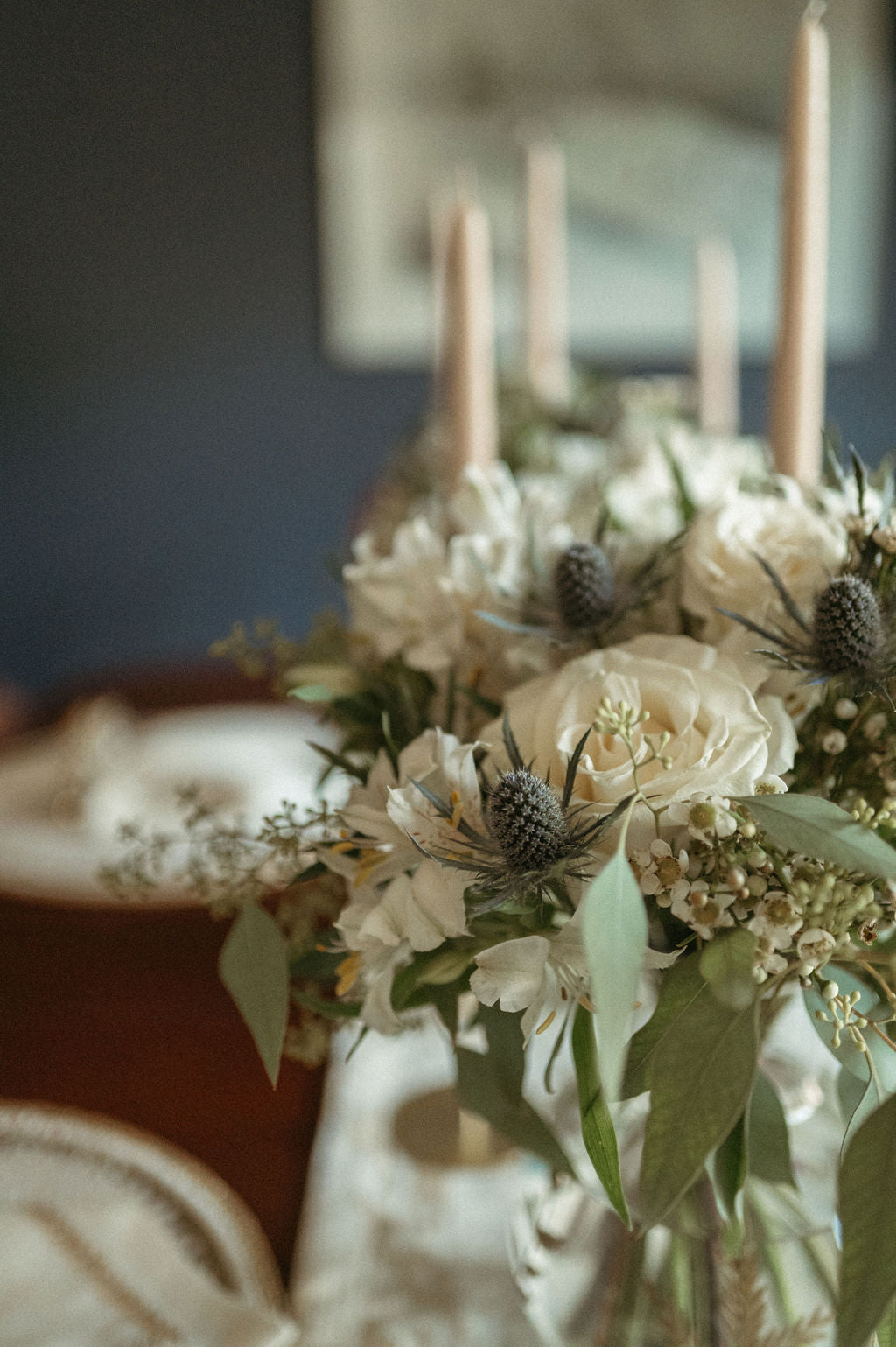 Decorative floral arrangement with candles on a table against a blurred background