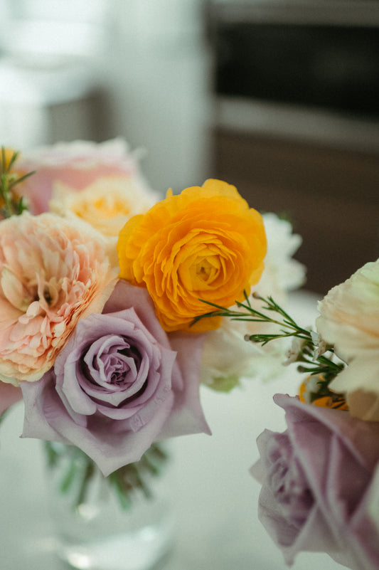 Bouquet of flowers with yellow, pink, and purple roses on a blurred background