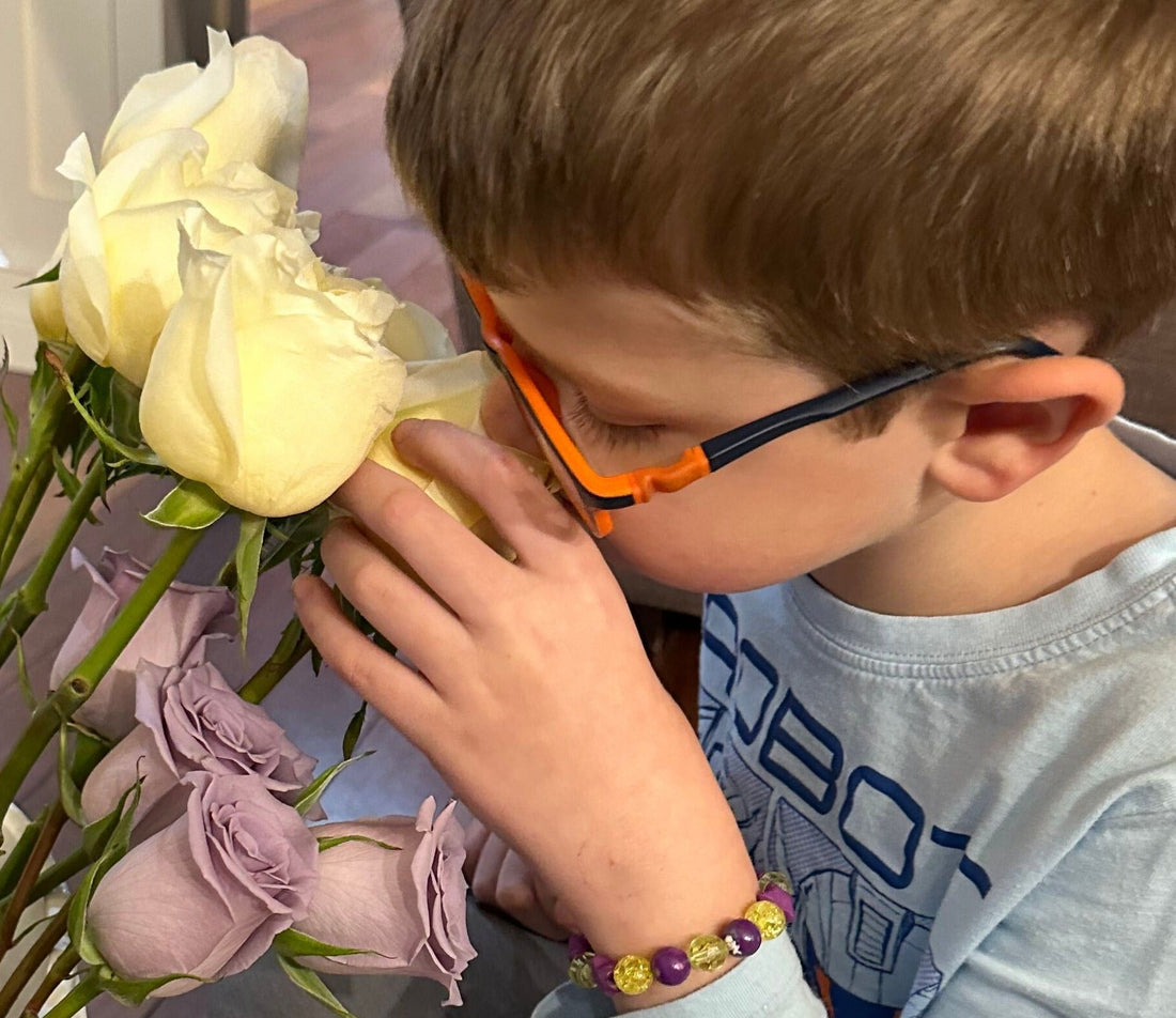 Small boy with his nose in the a white and purple roses.