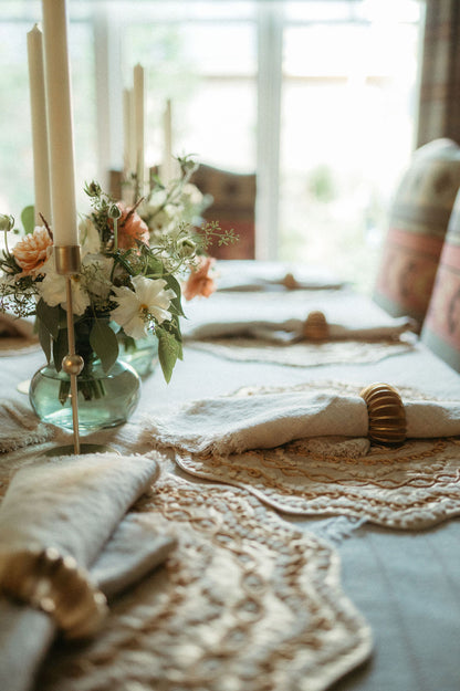 Elegant table setting with floral arrangement, candles, and decorative napkins.