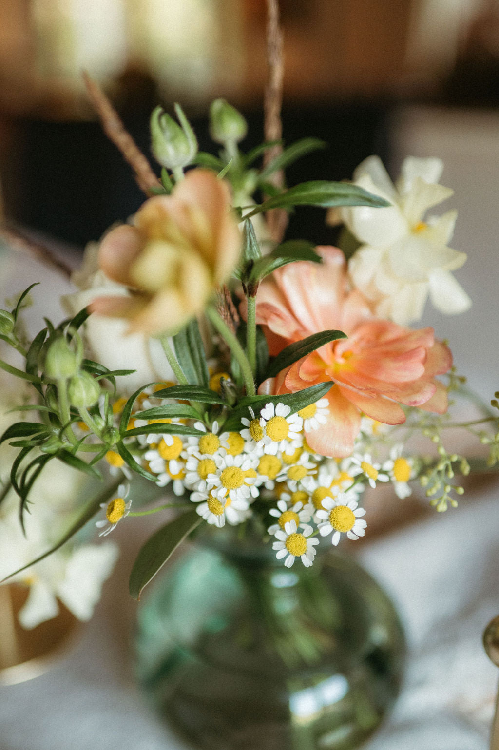 Bouquet of flowers with peach and white colors in a green vase on a blurred background