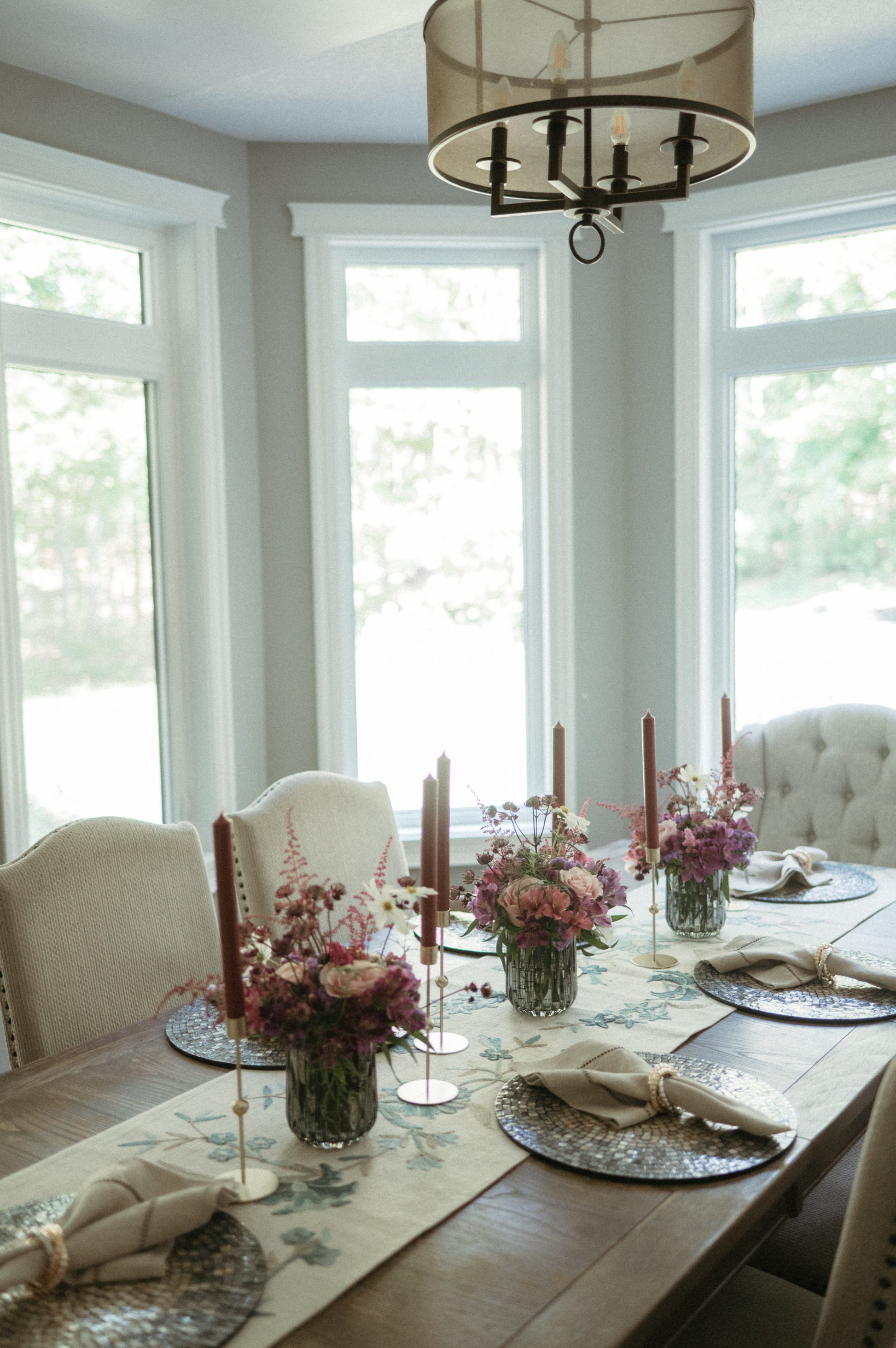 Dining room with a table set for a meal, featuring flowers and candles.
