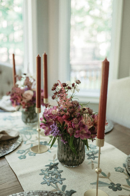 Table setting with pink candles, floral arrangement, and decorative placemats.