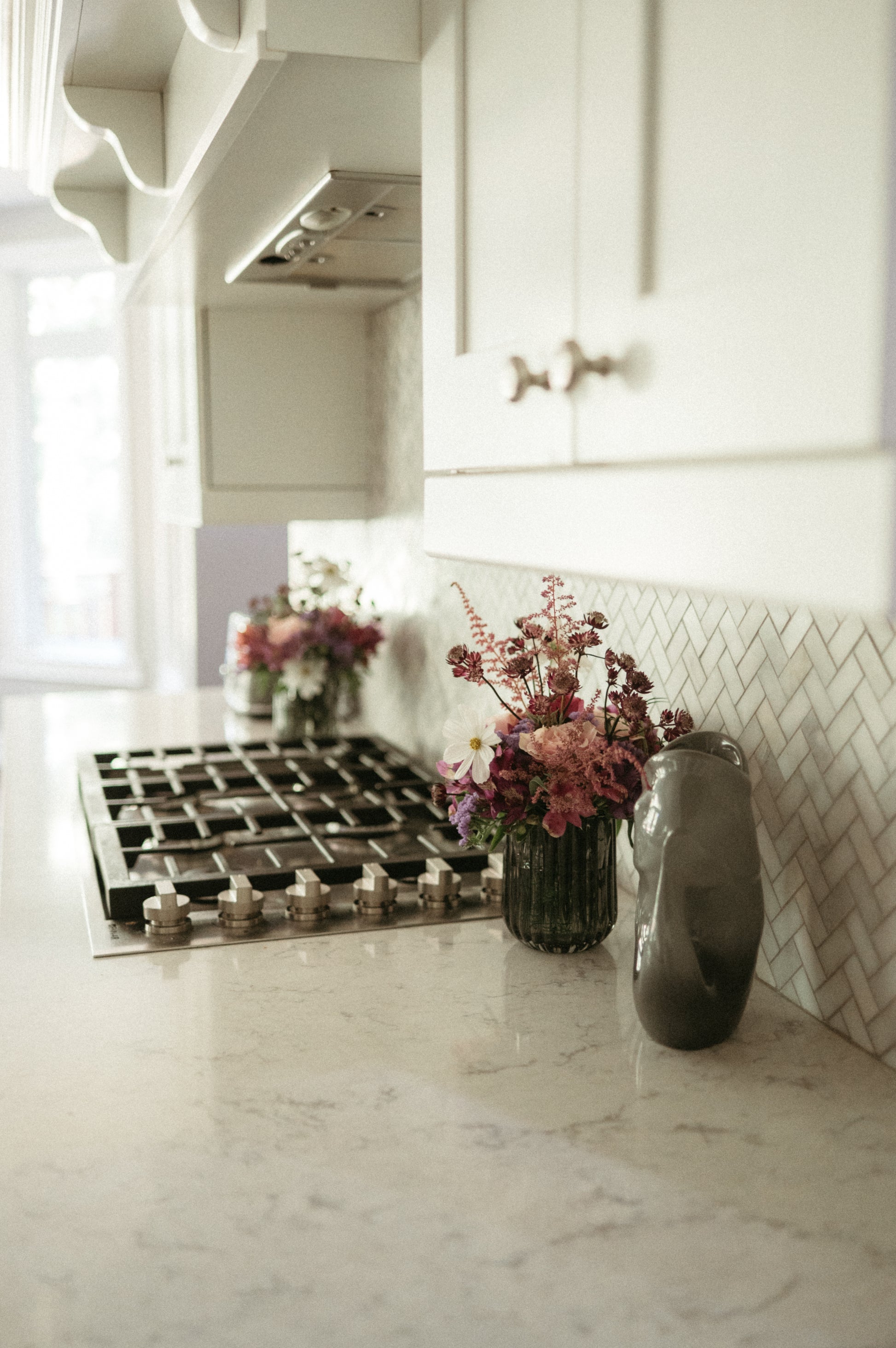 Kitchen counter with stove, decorative vases, and flowers.
