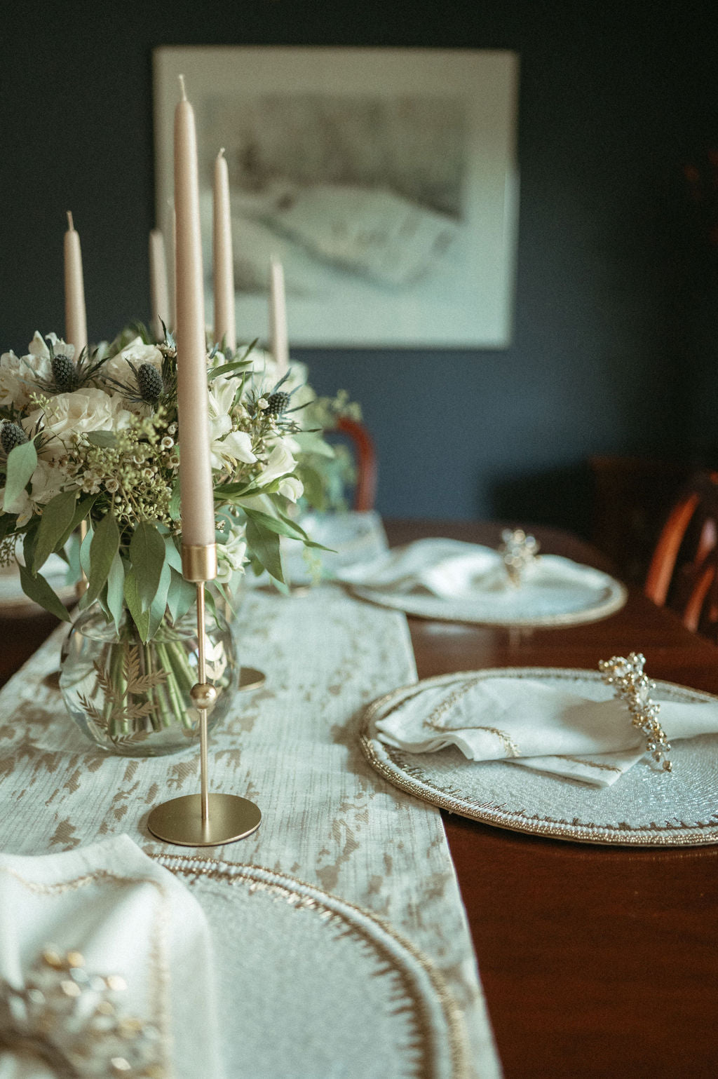 Elegant table setting with candles, flowers, and decorative plates in a cozy room.