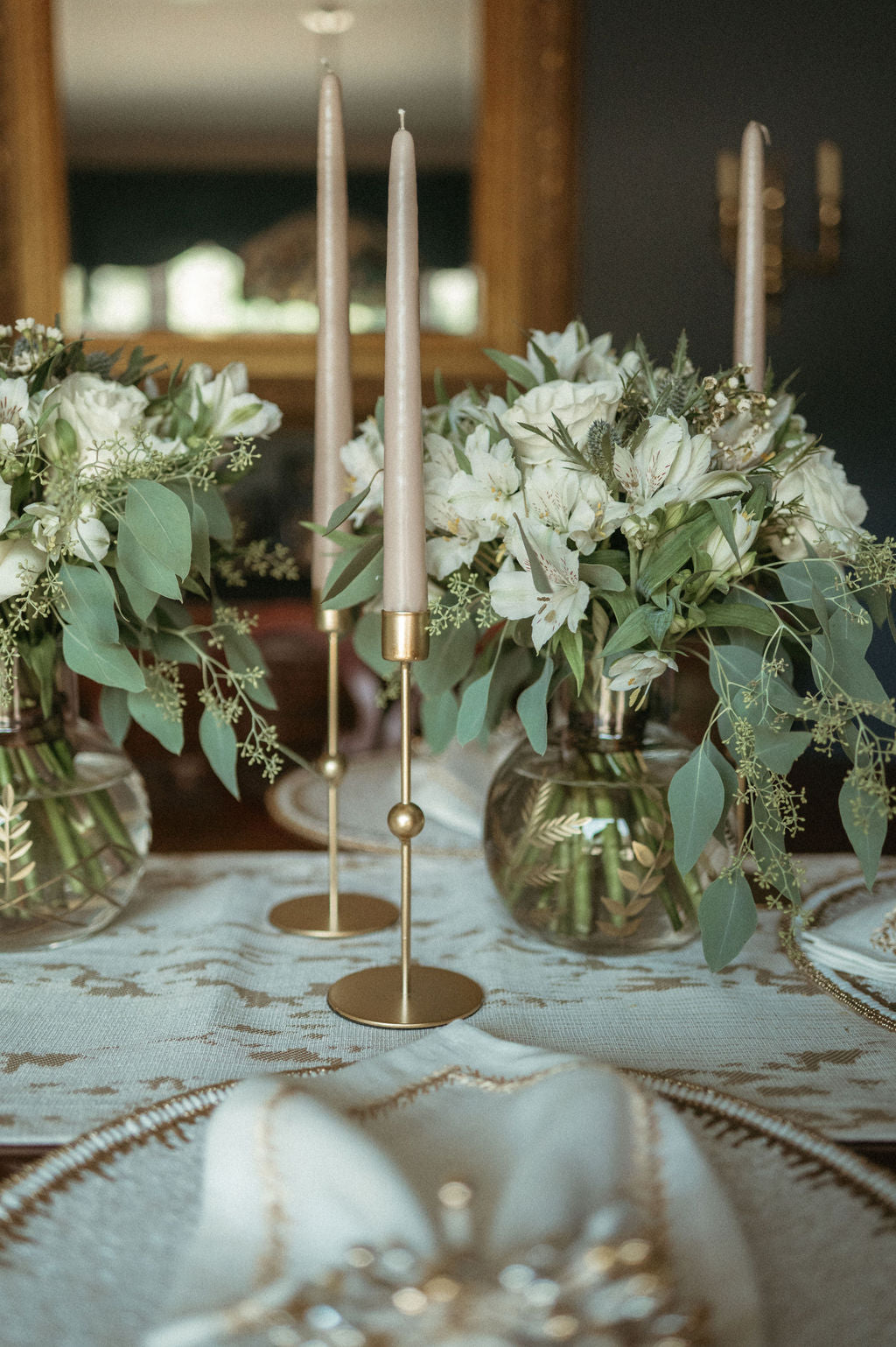 Decorative table setting with floral arrangements, candles, and a textured tablecloth.