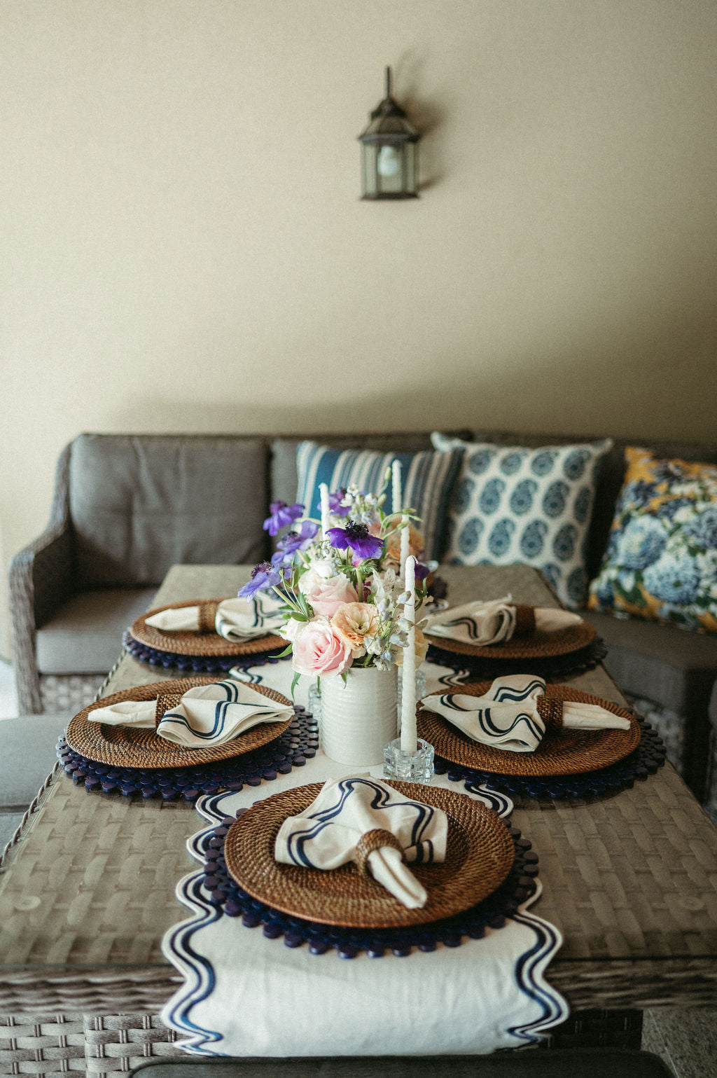 Decorative table setting with plates, napkins, and a vase of flowers on a table in a living room.
