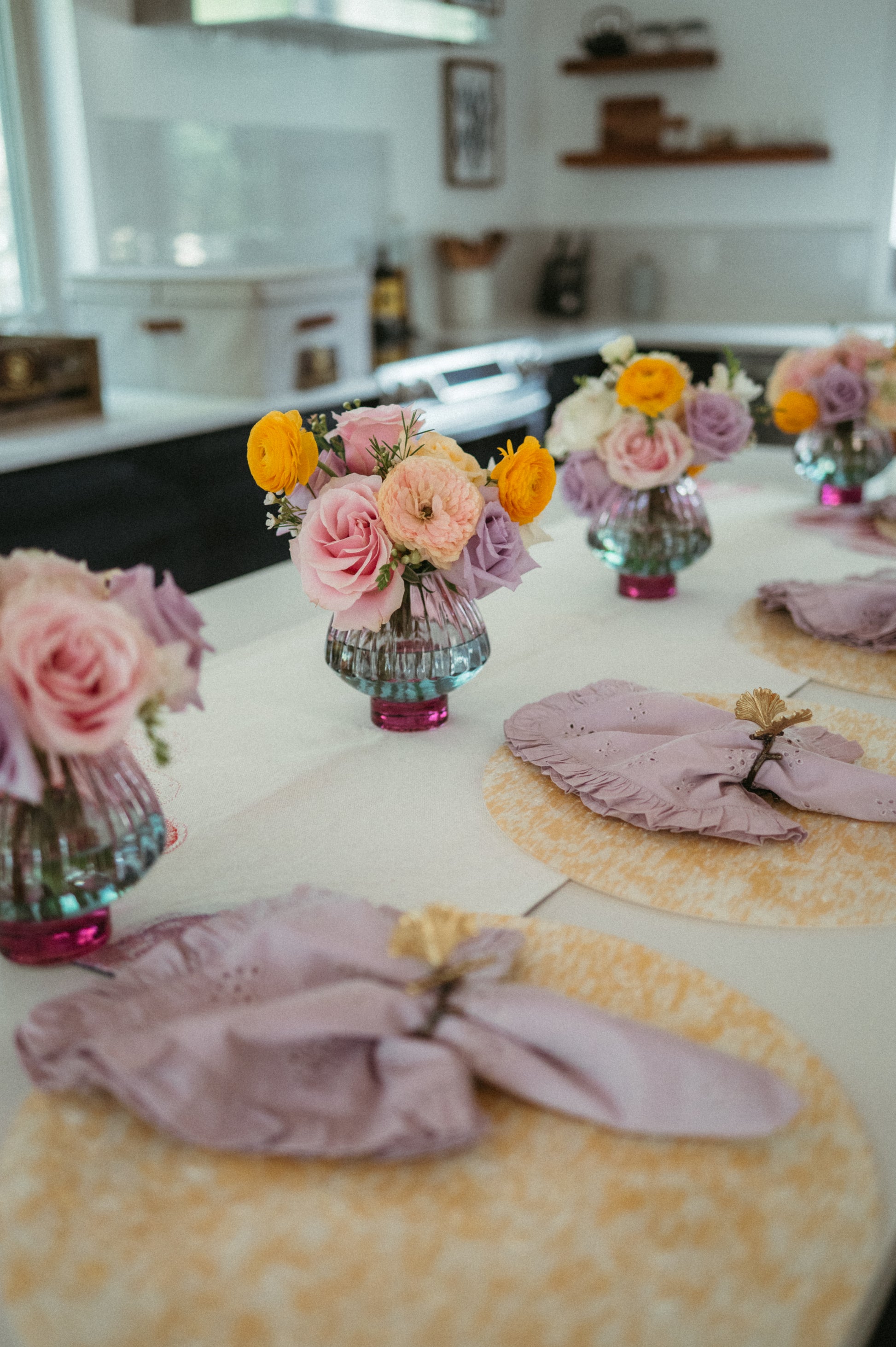 Decorative table setting with floral arrangements and pink napkins in a kitchen.