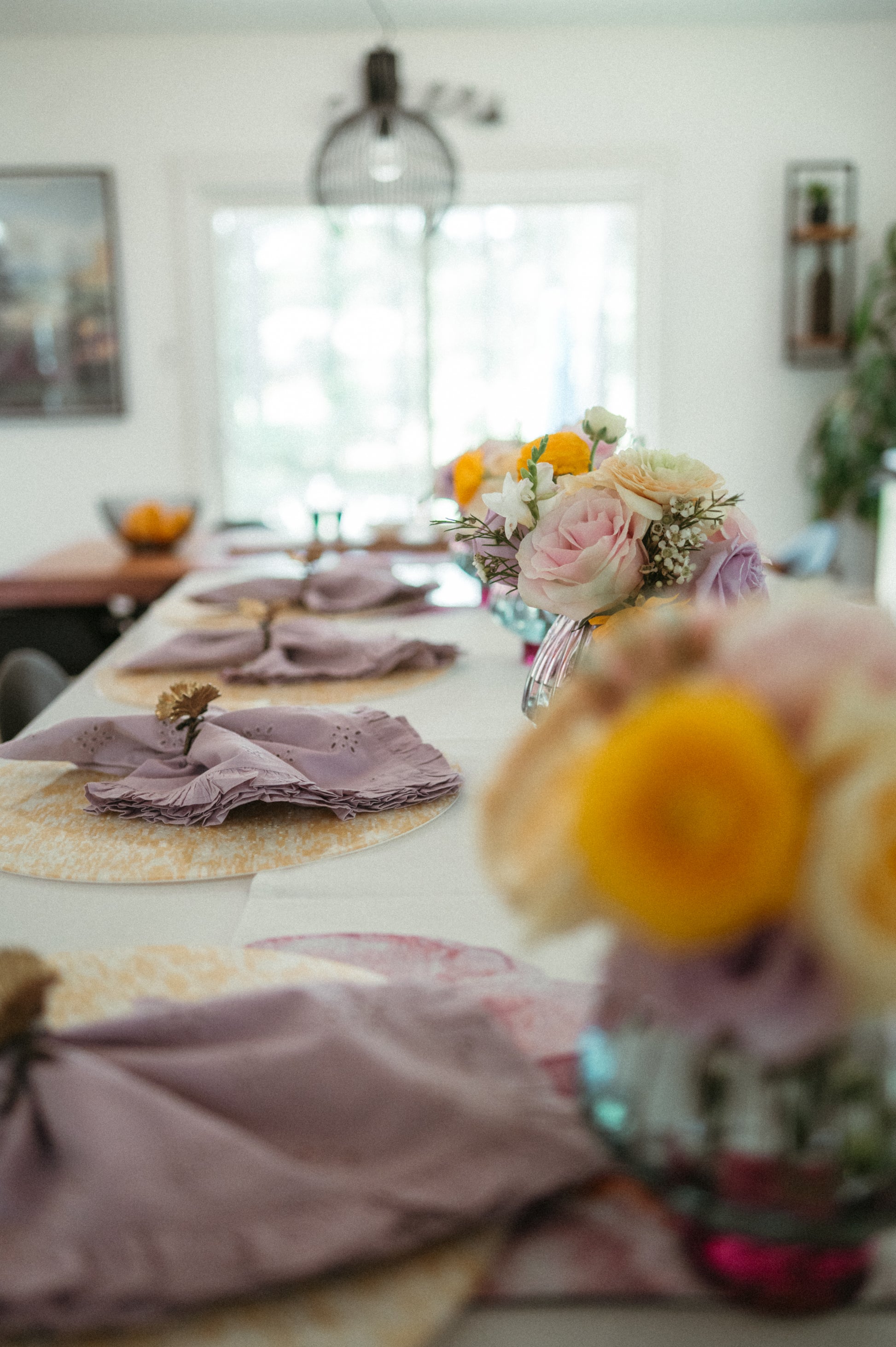 Decorative table setting with flowers and place settings in a room.